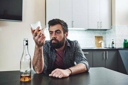 A man sitting with a glass of alcohol.